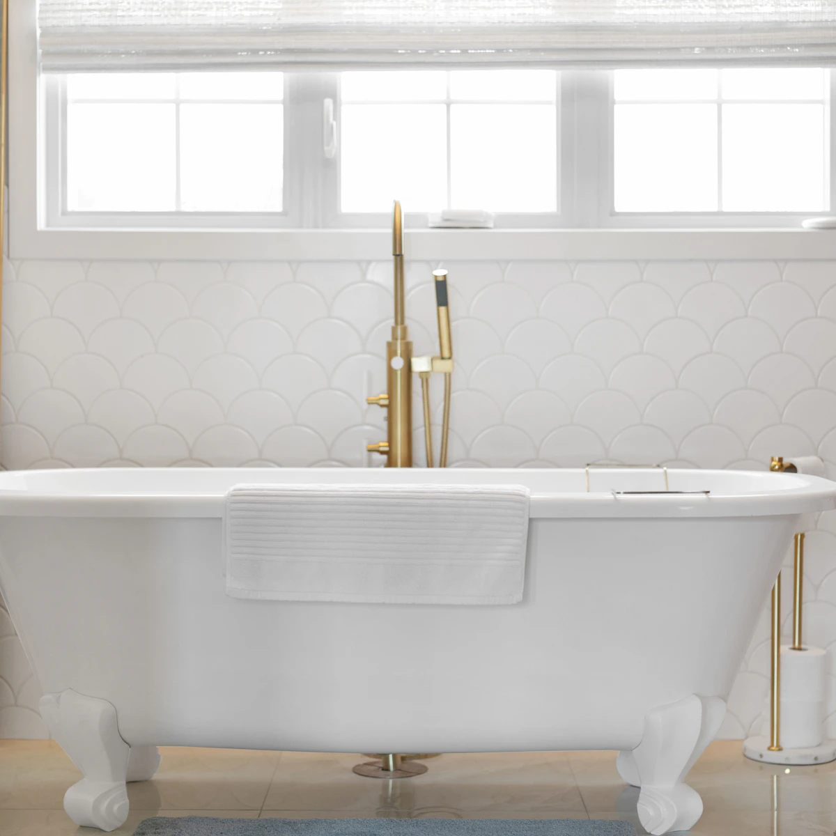 Spotless white clawfoot bathtub with polished gold fixtures after a deep cleaning